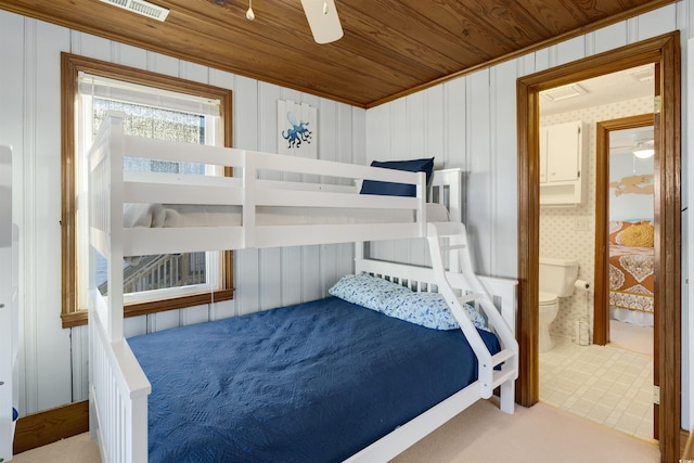 bedroom featuring ceiling fan, wood ceiling, wood walls, and connected bathroom