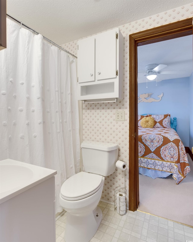 bathroom with ceiling fan, a textured ceiling, toilet, and vanity