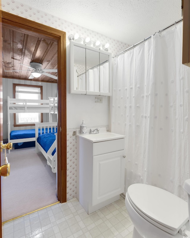 bathroom featuring ceiling fan, a textured ceiling, toilet, and vanity