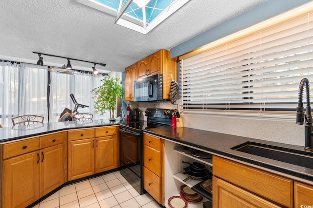 kitchen with a textured ceiling, black appliances, rail lighting, sink, and light tile patterned floors