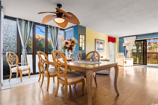 dining room with ceiling fan, expansive windows, light wood-type flooring, and a textured ceiling