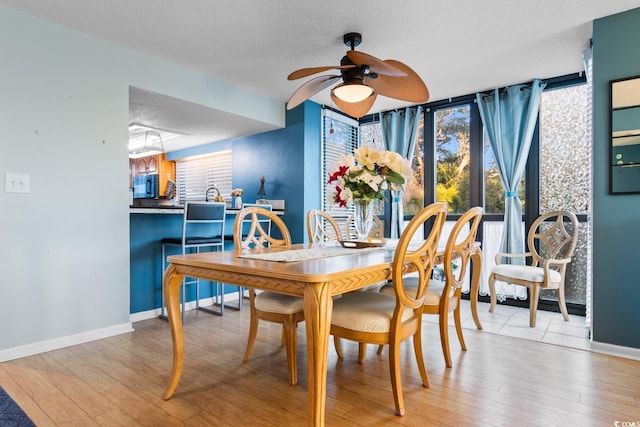 dining area with ceiling fan, a textured ceiling, and light wood-type flooring