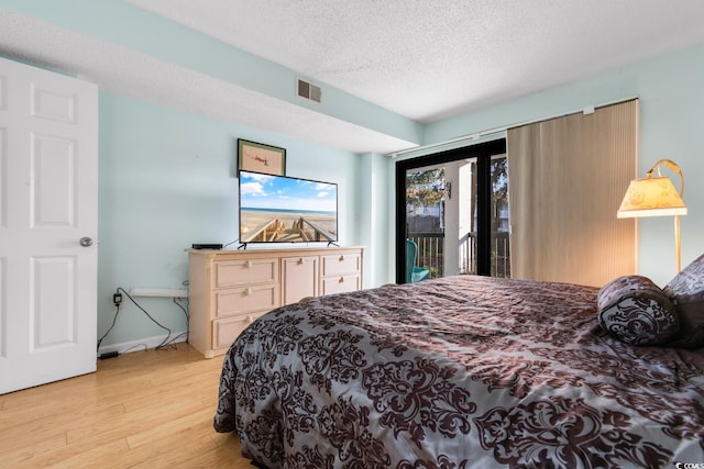 bedroom featuring a textured ceiling, light hardwood / wood-style floors, and access to outside