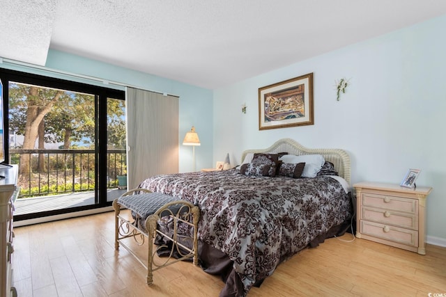 bedroom with access to exterior, a textured ceiling, and light hardwood / wood-style flooring