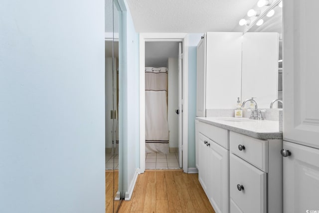 bathroom featuring a textured ceiling, a shower with shower curtain, hardwood / wood-style floors, and vanity