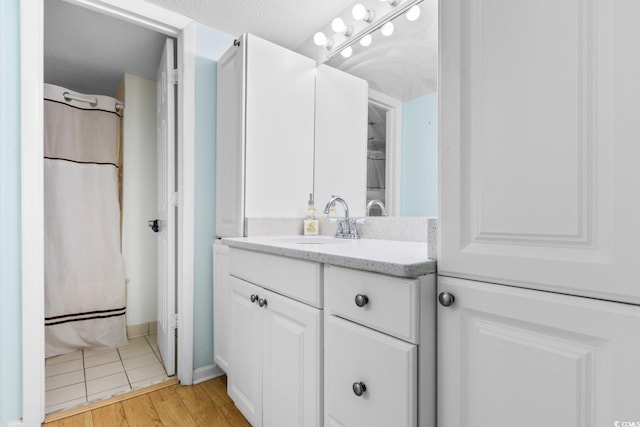 bathroom with hardwood / wood-style flooring, a textured ceiling, vanity, and a shower with curtain