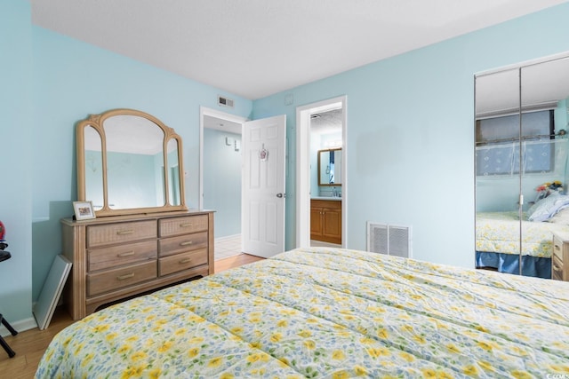 bedroom featuring ensuite bathroom and light wood-type flooring