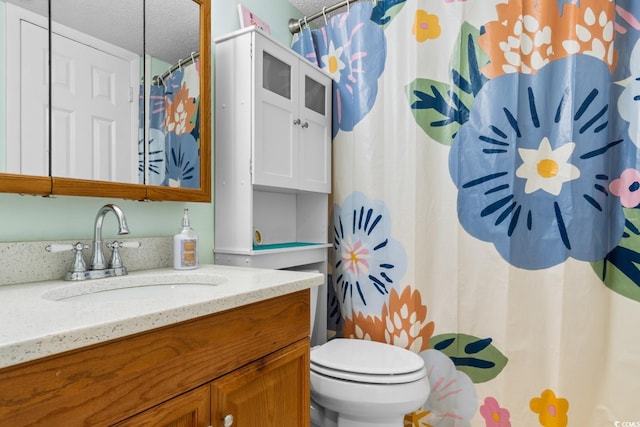 bathroom with a textured ceiling, toilet, and vanity