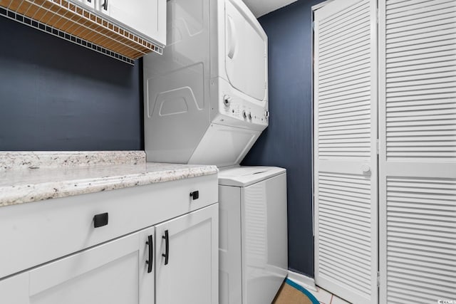 washroom featuring cabinets and stacked washer and clothes dryer