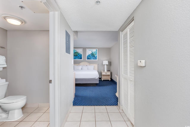 interior space with a textured ceiling, toilet, and tile patterned flooring