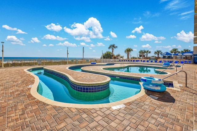 view of swimming pool featuring a water view and a patio