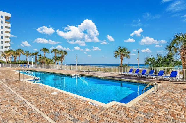 view of swimming pool with a patio area and a water view