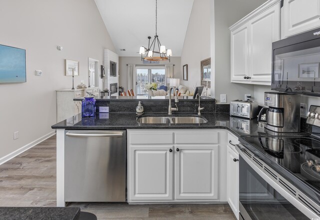 kitchen with appliances with stainless steel finishes, a chandelier, white cabinets, and sink