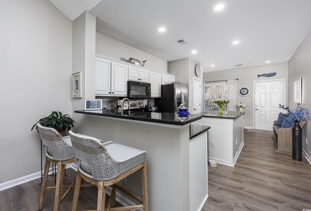 kitchen with a kitchen breakfast bar, white cabinets, kitchen peninsula, and stainless steel fridge with ice dispenser