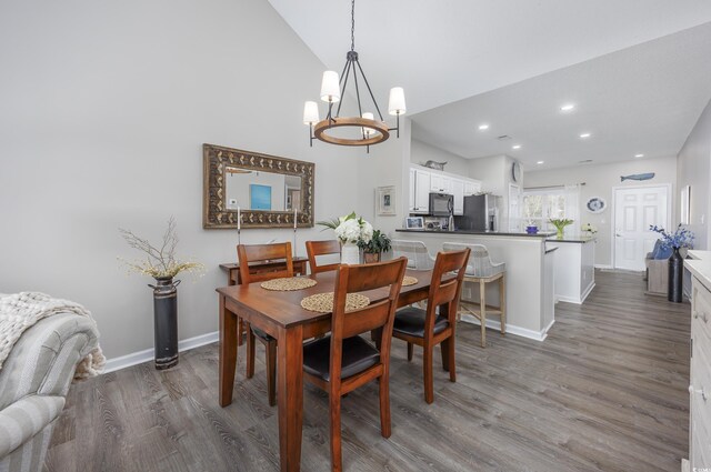 dining area featuring vaulted ceiling, dark hardwood / wood-style flooring, and a chandelier