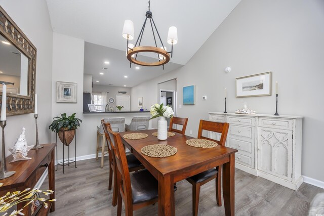 dining area featuring hardwood / wood-style flooring, a notable chandelier, and vaulted ceiling