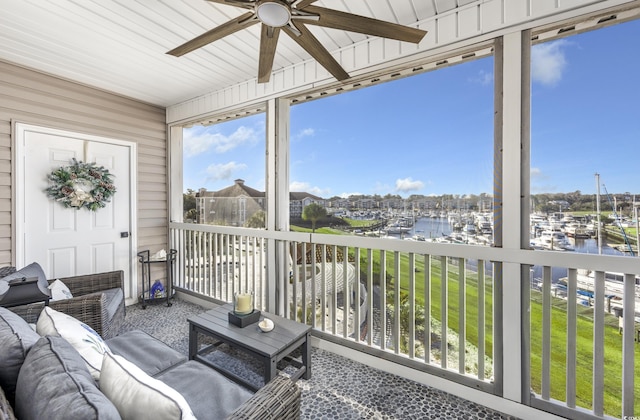 sunroom / solarium with ceiling fan and a water view