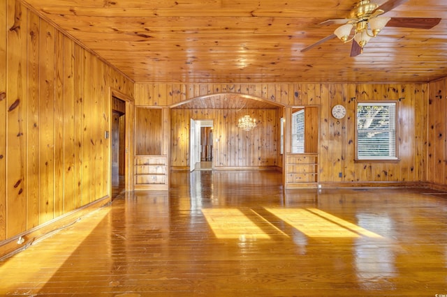 unfurnished living room with ceiling fan, wood ceiling, hardwood / wood-style flooring, and wooden walls