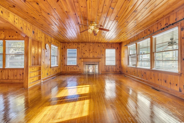 unfurnished living room with ceiling fan, wood ceiling, a wealth of natural light, and hardwood / wood-style floors