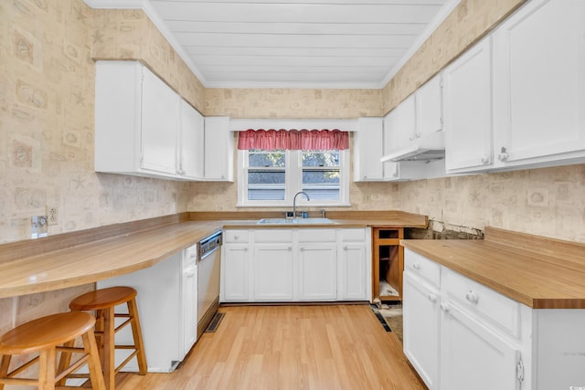 kitchen with white cabinetry, a kitchen bar, wooden counters, and sink