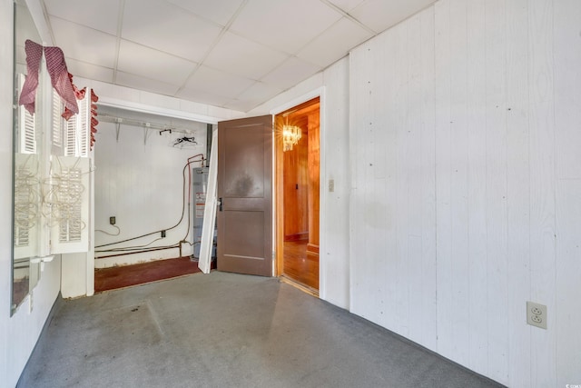 basement with gas water heater, a drop ceiling, and wood walls