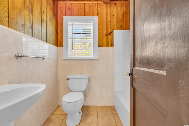 bathroom featuring toilet, tile patterned flooring, tile walls, and a tub