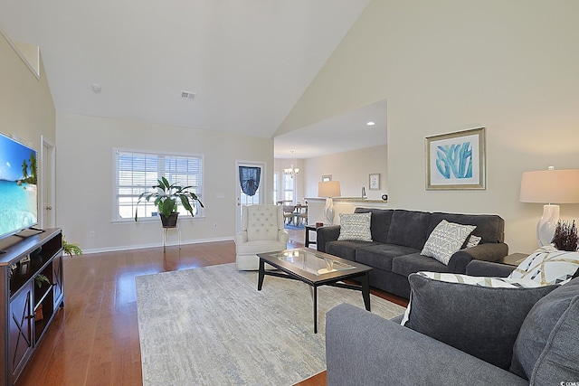 living room featuring an inviting chandelier, hardwood / wood-style flooring, and high vaulted ceiling