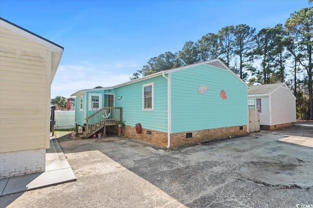 view of side of home featuring crawl space and fence