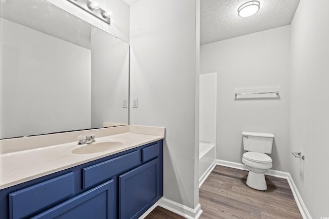 full bathroom featuring a textured ceiling, wood-type flooring, vanity, shower / washtub combination, and toilet