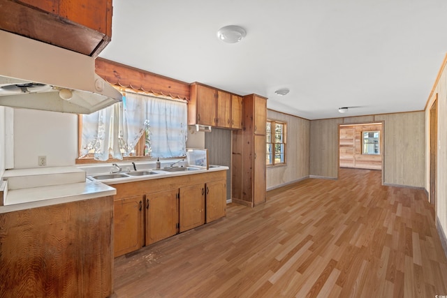 kitchen with light countertops, light wood finished floors, a sink, and brown cabinets