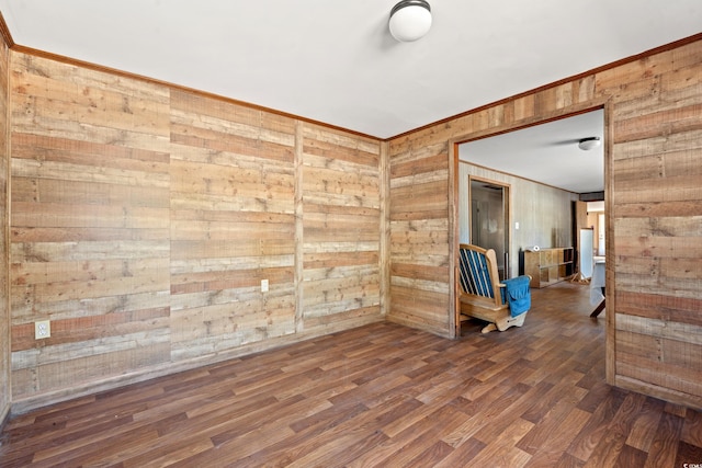 spare room featuring dark wood-style floors, wooden walls, and crown molding