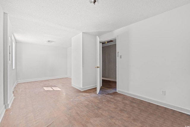 unfurnished room with light wood-style floors, a textured ceiling, and baseboards