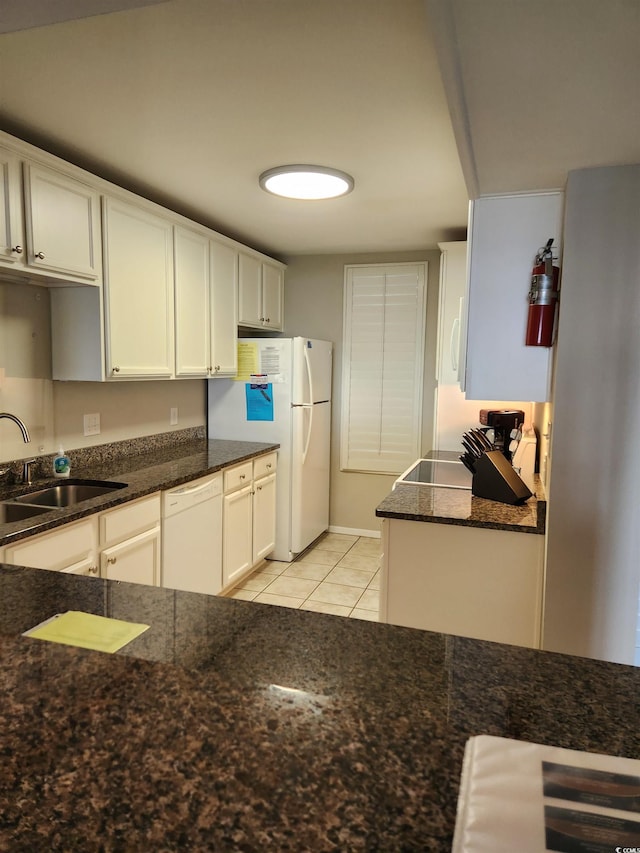 kitchen featuring white appliances, white cabinetry, dark stone counters, sink, and light tile patterned flooring