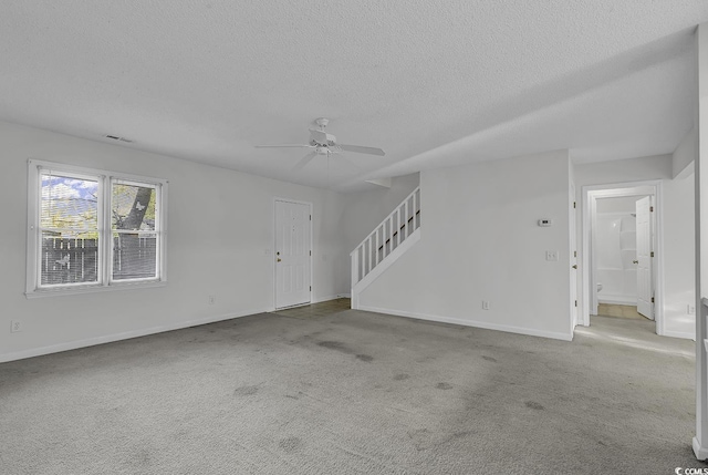 unfurnished living room featuring a textured ceiling, ceiling fan, and light colored carpet