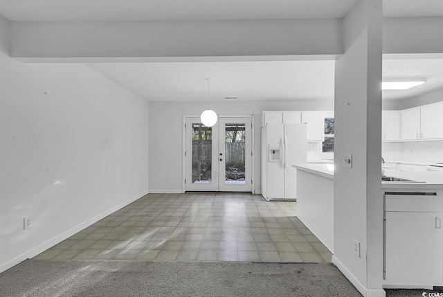 unfurnished dining area featuring light colored carpet, french doors, and sink