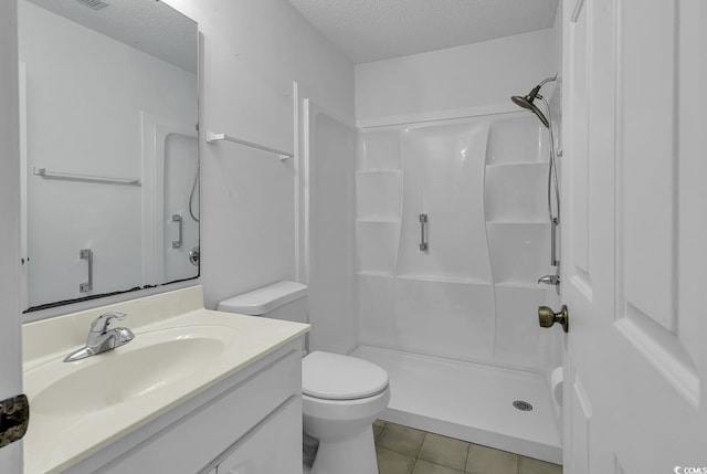 bathroom featuring toilet, vanity, tile patterned floors, a shower, and a textured ceiling