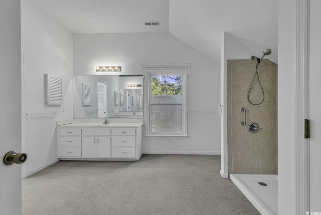 bathroom with vanity, vaulted ceiling, and a tile shower