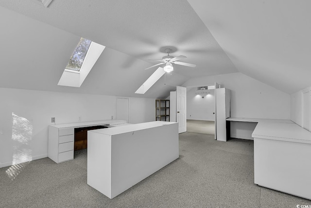 interior space featuring ceiling fan, a textured ceiling, and lofted ceiling with skylight