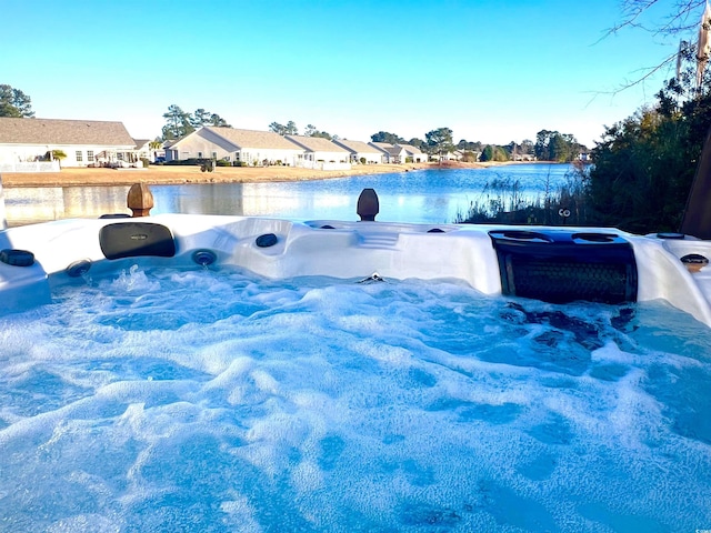 view of swimming pool featuring a water view and a hot tub