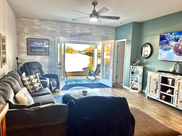 living room with ceiling fan, light hardwood / wood-style flooring, and wooden walls