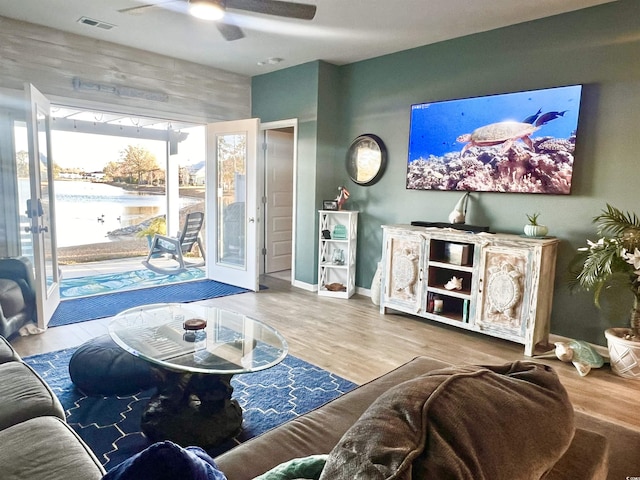 living room featuring ceiling fan, hardwood / wood-style floors, and wood walls