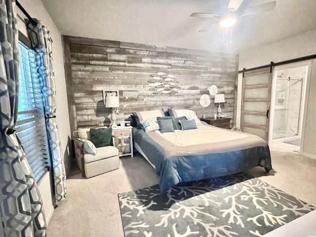 bedroom with ceiling fan, a barn door, and wood walls