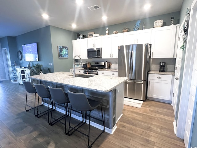 kitchen featuring white cabinets, appliances with stainless steel finishes, sink, and an island with sink