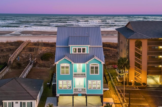 aerial view at dusk with a water view and a beach view