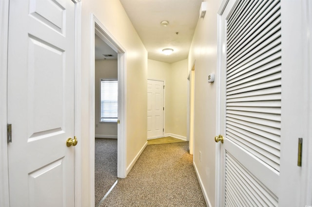 hall featuring baseboards, visible vents, and light colored carpet