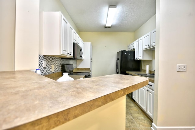 kitchen with white cabinetry, a sink, a textured ceiling, a peninsula, and black appliances