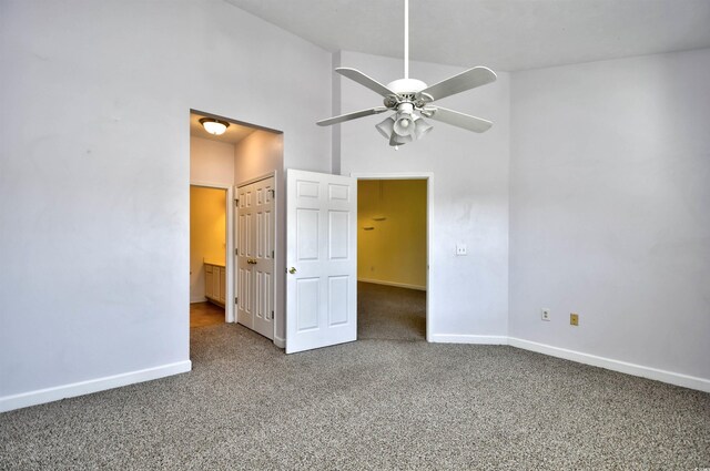 unfurnished bedroom with ceiling fan, carpet floors, a towering ceiling, and baseboards