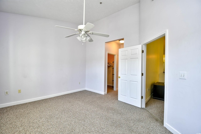 unfurnished bedroom featuring ceiling fan, a spacious closet, baseboards, and carpet flooring