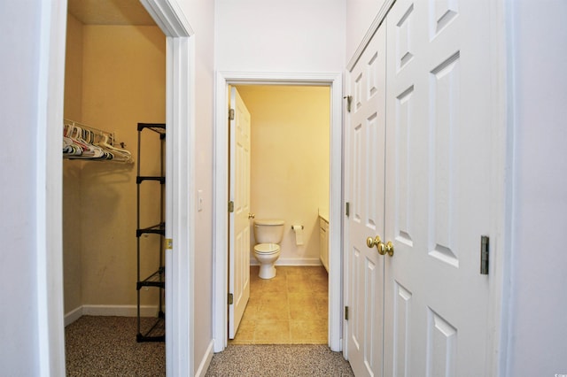 hallway with carpet, baseboards, and tile patterned flooring