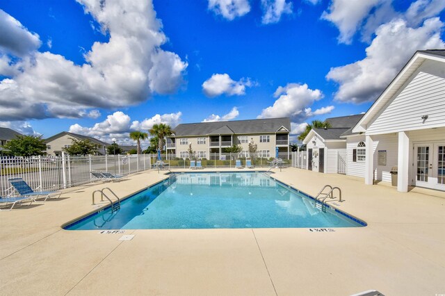 community pool featuring french doors, fence, and a patio